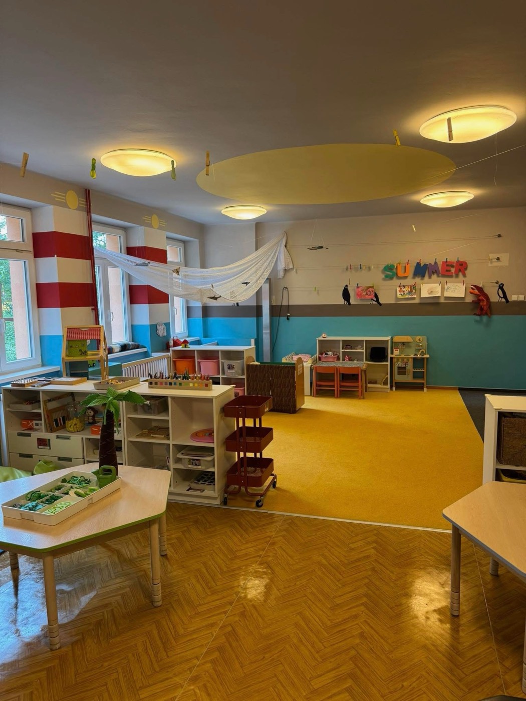 Herna mateřské školy se žlutým kobercem a hracími koutky