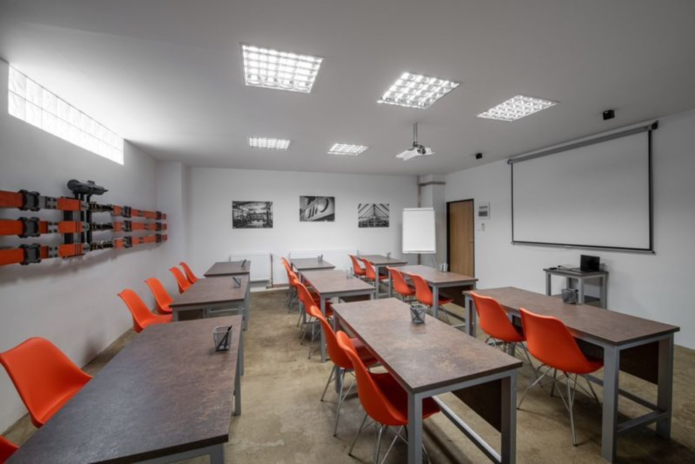 Školicí místnost s oranžovými židlemi a projekčním plátnem